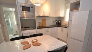 A modern kitchen with white cabinets, a stainless steel oven, a microwave, and a refrigerator. - Beautiful apartment for 6 people with WIFI, A/C, TV and terrace (Salou)