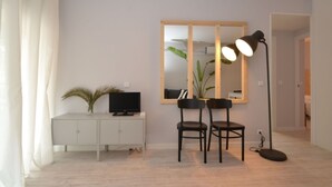 A modern living room with a TV, a cabinet, two chairs, a large mirror, and a floor lamp. - Beautiful apartment for 6 people with WIFI, A/C, TV and terrace (Salou)