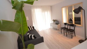 A modern living room with a grey sofa, a large mirror, and a floor lamp. - Beautiful apartment for 6 people with WIFI, A/C, TV and terrace (Salou)