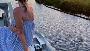 A person on a boat docked at a river with a sunset in the background.