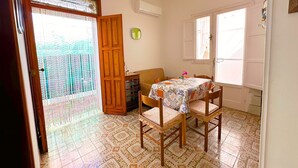 Un comedor con una mesa dispuesta para cuatro personas, un armario de madera y un reloj en la pared.