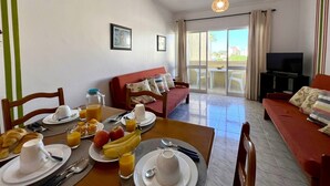 Un salon bien éclairé comprenant un coin repas, un canapé, un téléviseur et un balcon avec vue.