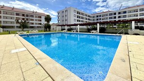 A swimming pool with clear blue water, surrounded by a tiled deck. - VILAMOURA MARINA CHARMING WITH POOL by HOMING (Vilamoura)