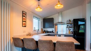 Een moderne keuken met een centraal eiland, barkrukken en een zwarte koelkast.