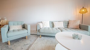 Un salon avec un canapé bleu clair, un fauteuil assorti, une table basse blanche et un lampadaire.