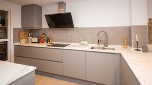 Eine moderne Küche mit Einbauofen, Spüle aus Edelstahl und Schneidebrett aus Holz.