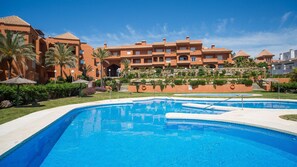 Ein Resort mit Schwimmbad, Palmen und einem Gebäude mit mehreren Balkonen.