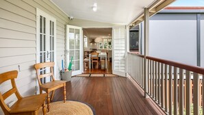 Une terrasse en bois avec une rambarde, une chaise et une porte donnant sur un espace intérieur.