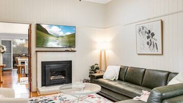Een woonkamer met een open haard, een bank, een salontafel en een televisie boven de haard.