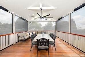 A covered patio with a dining table and chairs, a ceiling fan, and a view of the outdoors.