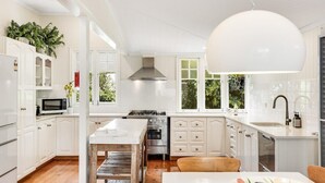 Une cuisine moderne avec des meubles blancs, un îlot central et un grand luminaire suspendu.