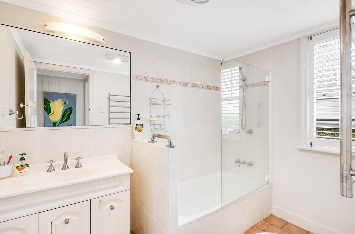 A bathroom with a white vanity, a glass shower enclosure, and a large mirror.
