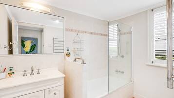 A bathroom with a white vanity, a glass shower enclosure, and a large mirror.
