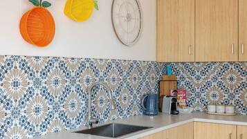 Una cocina con salpicadero decorativo, armarios de madera, un fregadero y un mural con frutas.