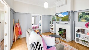 Una sala de estar con sofá, televisión, chimenea y estantería.