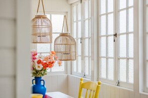 A room with a table and chairs, large windows, and hanging wicker lamps. - "Camellia Cottage"! CDB Diamond! (Toowoomba City)