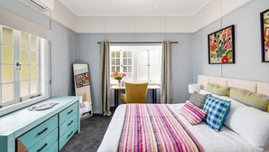 Un dormitorio con cama, escritorio, silla y ventana.
