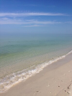 Een strand met helder water, een zandstrand en een heldere lucht.