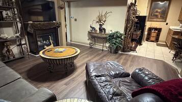 A living room with a fireplace, leather sofa, and a ceiling fan.