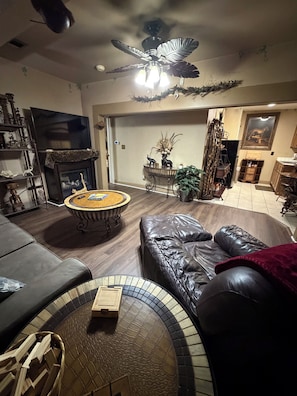 A living room with a fireplace, leather sofa, and a ceiling fan.