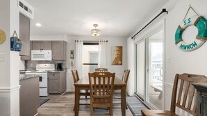 A modern kitchen with a dining area, a view through the glass door, and a life preserver decoration on the wall. - Canalfront 2 Bedroom-Sleeps 6-Laundry-WiFi (Ocean City)