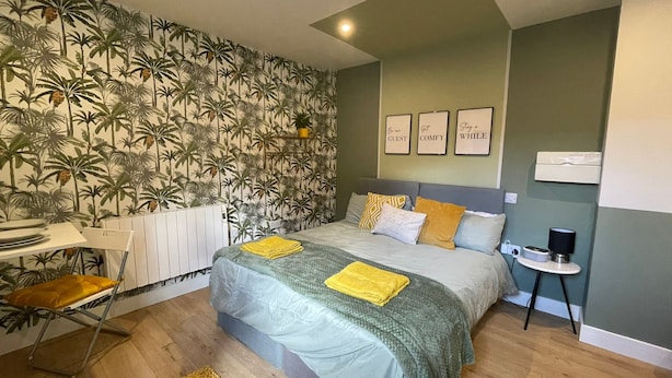 Um quarto com uma cama, uma escrivaninha e uma cadeira. Há três quadros na parede.