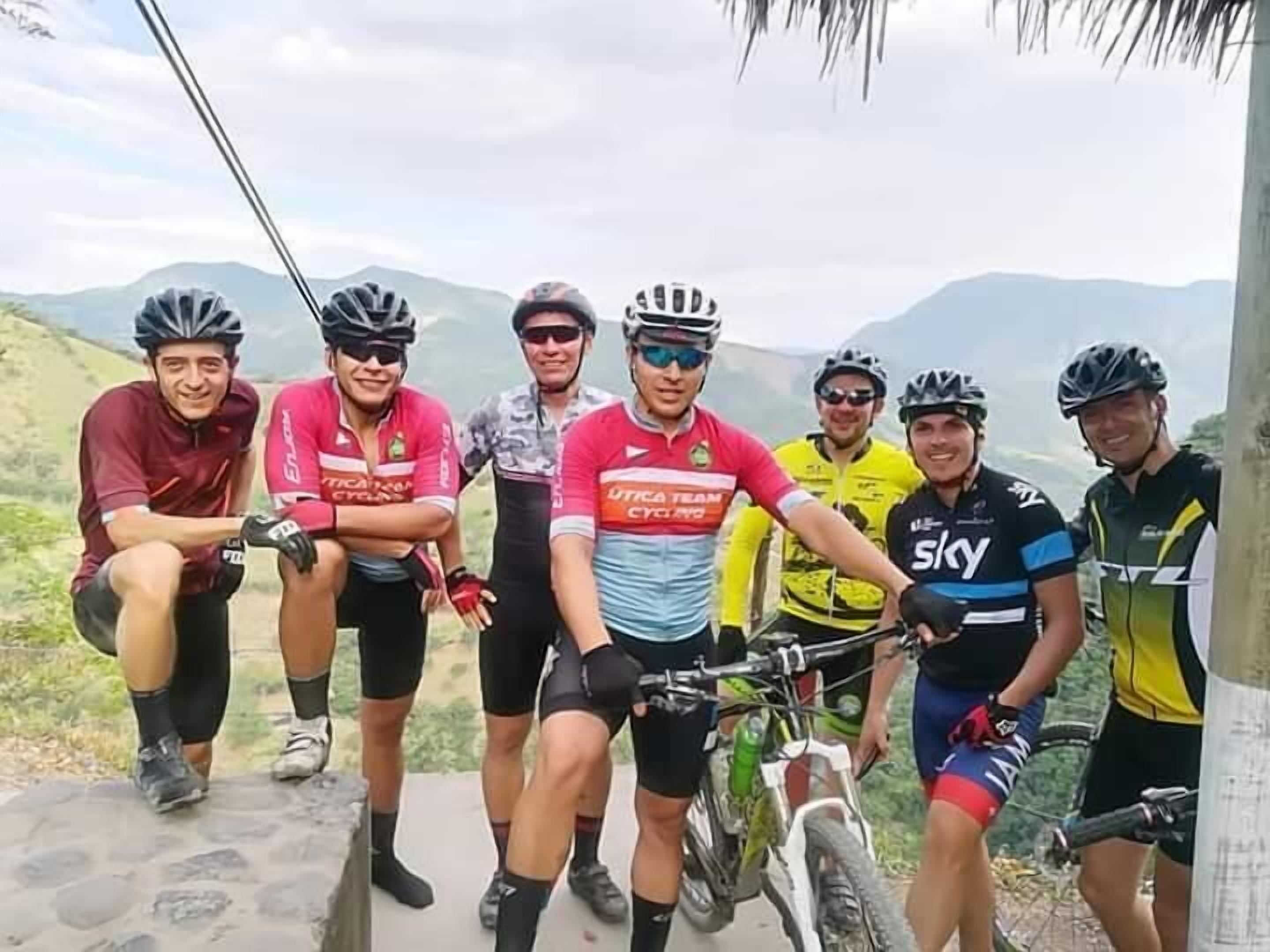 Um grupo de ciclistas posando em uma trilha de montanha, com uma vista panorâmica ao fundo.