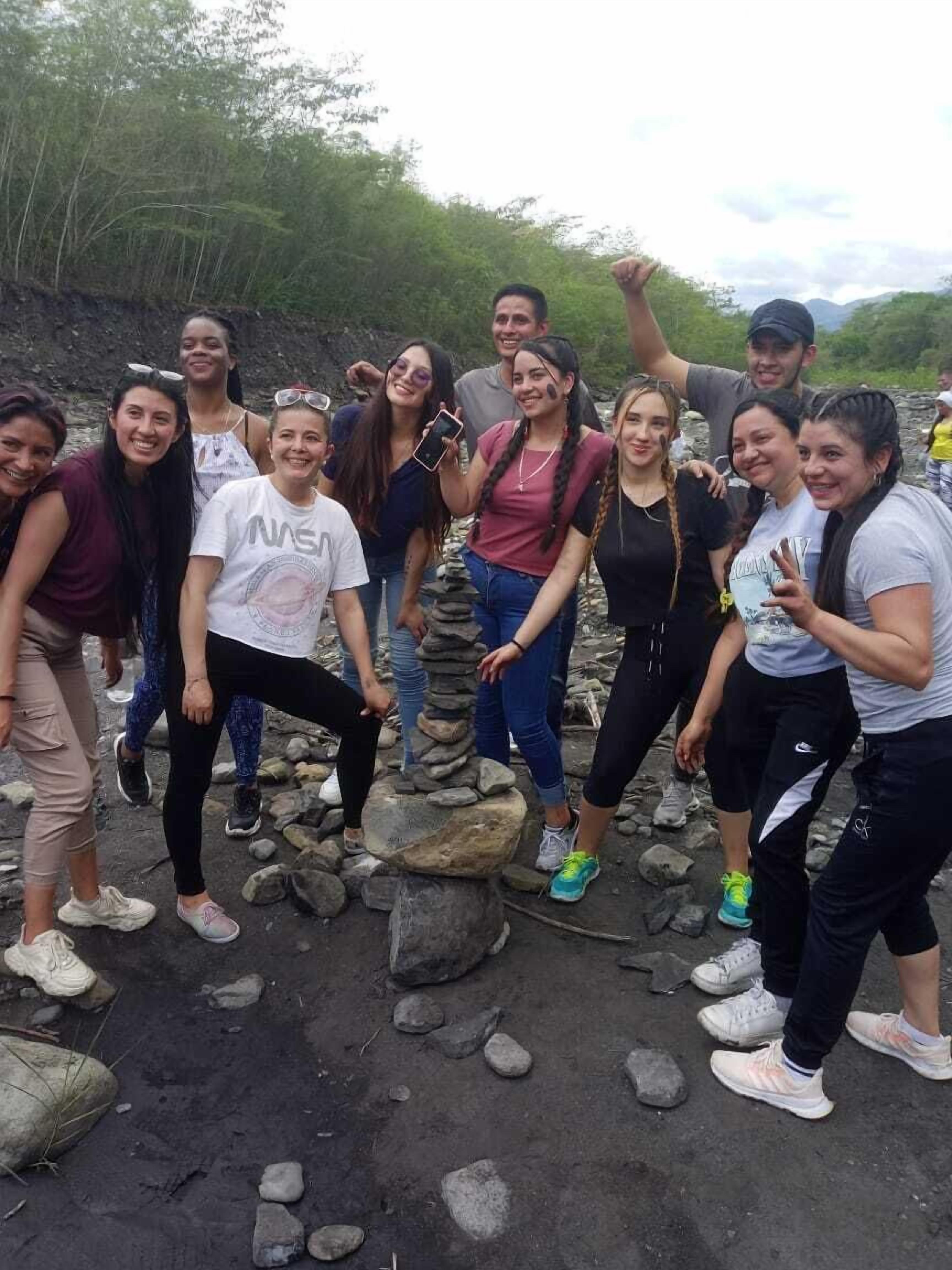 A group of people posing in front of a rocky landscape with trees in the background.