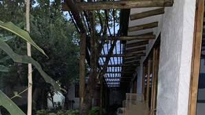 Ein überdachter Außenbereich mit Pool, einer Holzpergola und einer Sitzecke mit Stühlen.