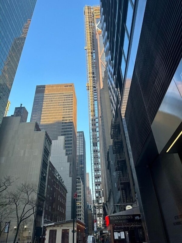 A cityscape with tall buildings, including a construction site on one of the skyscrapers.