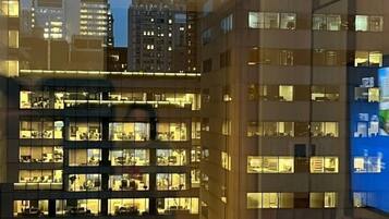 Un immeuble à plusieurs étages, doté de nombreuses fenêtres, qui ressemble probablement à un hôtel ou à un immeuble de bureaux, avec une tour imposante en arrière-plan.