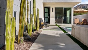 Een modern huis met een zwembad, cactussen en een terras.