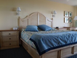 Een slaapkamer met een houten bed, twee nachtkastjes, een nachtkastje en een dressoir.