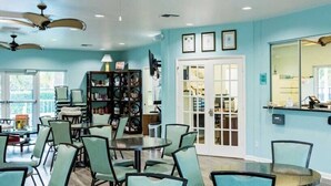 A room with teal walls, a large window, a reception desk, and a bookshelf.
