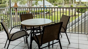 A balcony with a round table and four chairs, surrounded by a metal railing.