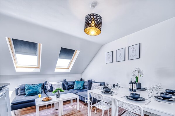 A modern loft apartment with a dining area, a sofa, and a ceiling light fixture.
