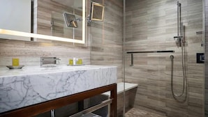 A modern bathroom with a marble vanity, a glass shower enclosure, and wooden paneling on the walls. - NYC | Midtown Location | Central Park | Studio Plus (New York)
