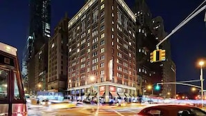 A multi-story building with a classic architectural style, featuring a prominent corner entrance and multiple windows. - NYC | Midtown Location | Central Park | Studio Plus (New York)