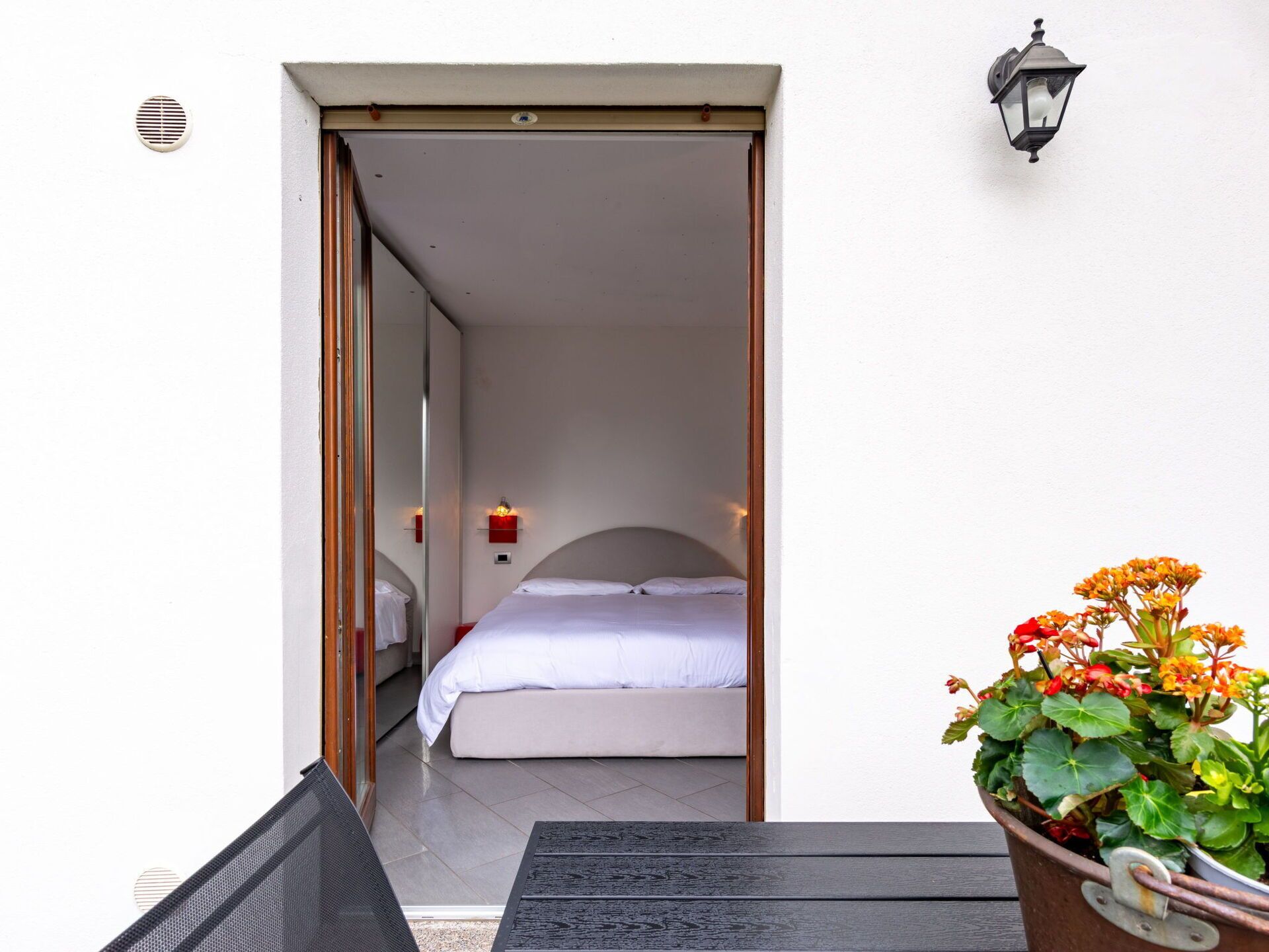 Une chambre à coucher avec un lit, une petite table et une plante en pot.