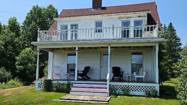A two-story house with a front porch, a chimney, and a small front yard. - Perry Shore Road Cottage (Perry)