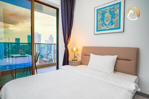 A hotel room with a bed, a nightstand, a lamp, a window with a view of the city, and a framed picture on the wall. - Phnom Penh Pool Hotel 24 USD M Residence (Phnom Penh)