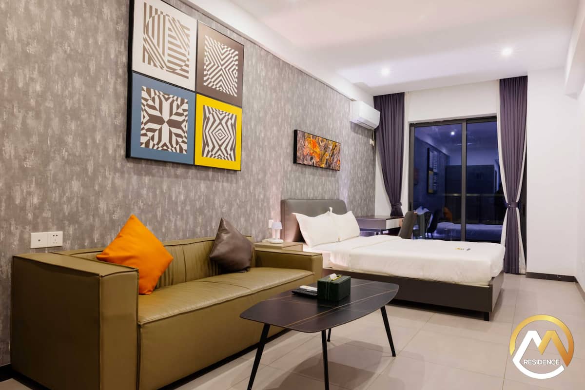 Una habitación de hotel moderna con sofá, cama, una mesita de café y obras de arte en la pared.