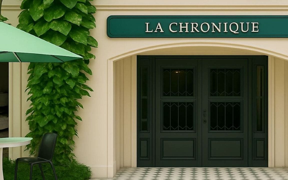 A building facade with a sign reading 'LA CHRONIQUE' above a dark green door with decorative glass panels.