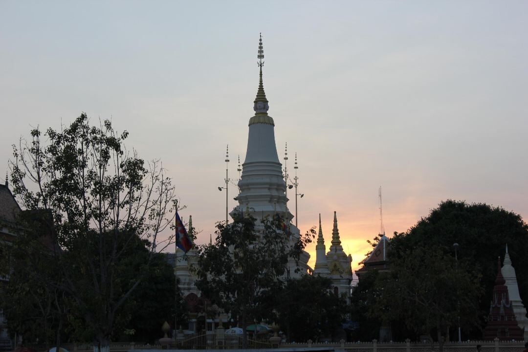 A large white pagoda with multiple tiers, surrounded by trees and smaller structures.