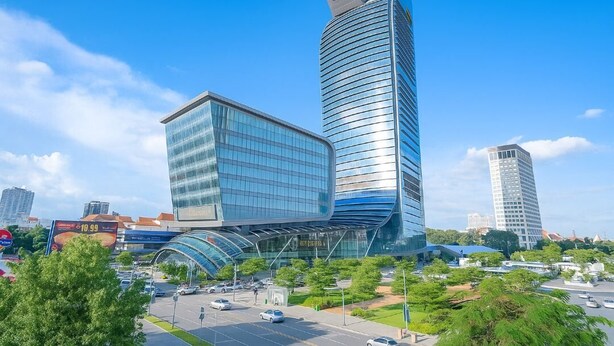 Un edificio moderno con fachada de vidrio curvo y una estructura cilíndrica alta.