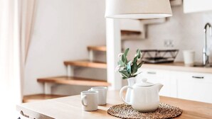 Un coin cuisine avec un plan de travail en bois, une bouilloire blanche et deux tasses blanches.