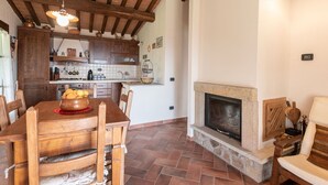 A rustic kitchen with wooden cabinets, a stone fireplace, and a dining area with a wooden table and chairs. - Beautiful private villa for 5 people with WIFI, TV, terrace and panoramic view (Roccastrada)
