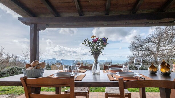 A table set for dining with a view of mountains, a vase with flowers, and a basket of bread. - Beautiful private villa for 5 people with WIFI, TV, terrace and panoramic view (Roccastrada)