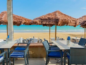 A beachside restaurant with tables and chairs, thatched umbrellas, and a view of the ocean. - Lovely apartment for 3 guests with A/C, TV and terrace (Peschici)