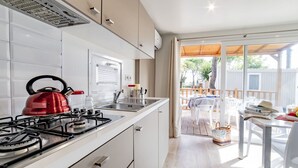 A modern kitchen with white cabinets, a red kettle, and a gas stove.